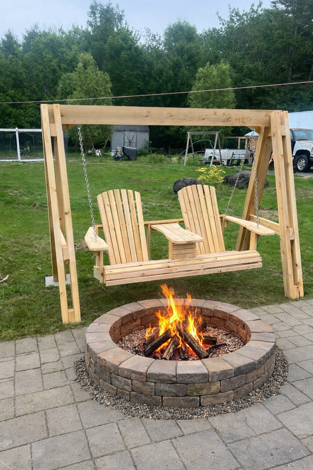 Cedar glider swing with a built-in center console, hung from an A-frame stand beside a stone fire pit