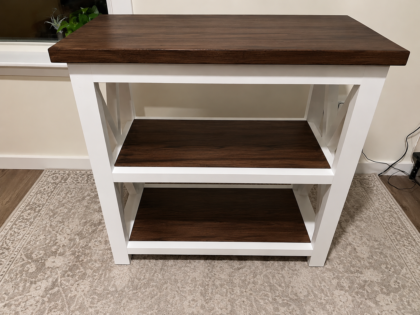 Two-tier white and walnut-finish side table with open shelving, styled on an area rug
